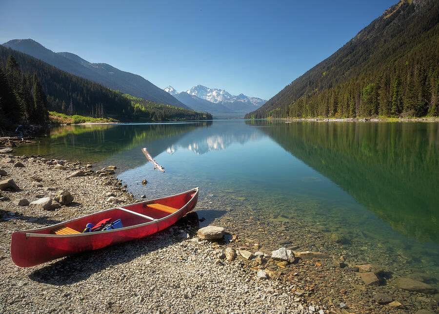 Red canoe on the shore of Duffey Lake with mountain reflections in British Columbia