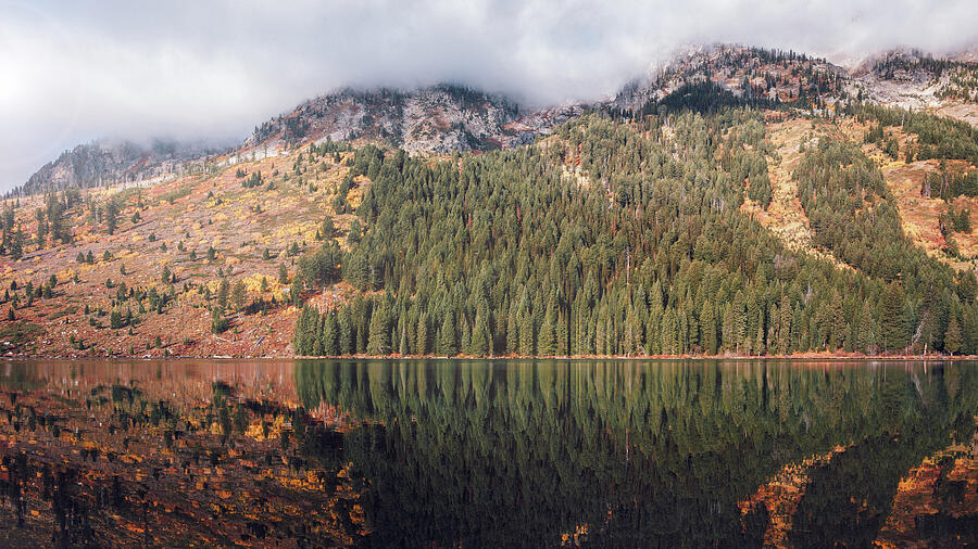 Fog and autumn forest reflected in String Lake beneath the mountains of Grand Teton National Park