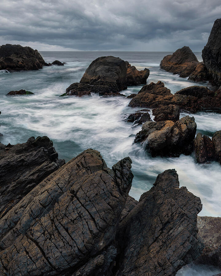 Stormy waves moving around dark rocks at Big Beach in Ucluelet British Columbia